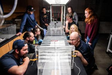 Students and Dr. Hancock gathered around a table, looking at mosquitos