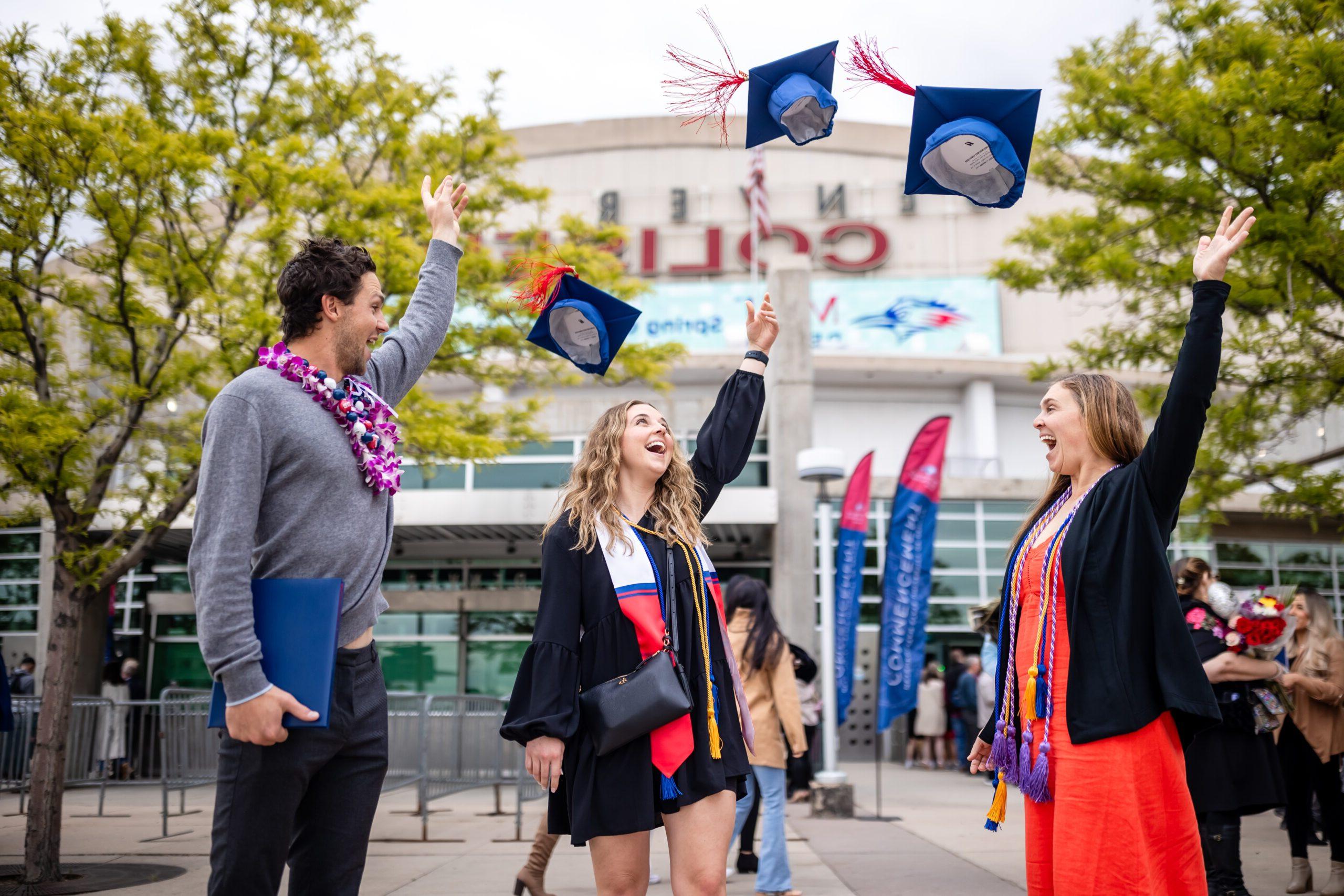 Three students throwing their caps into the air after the commencement ceremony.